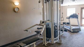 A fitness center with a bench press, cable machine, and a treadmill.
