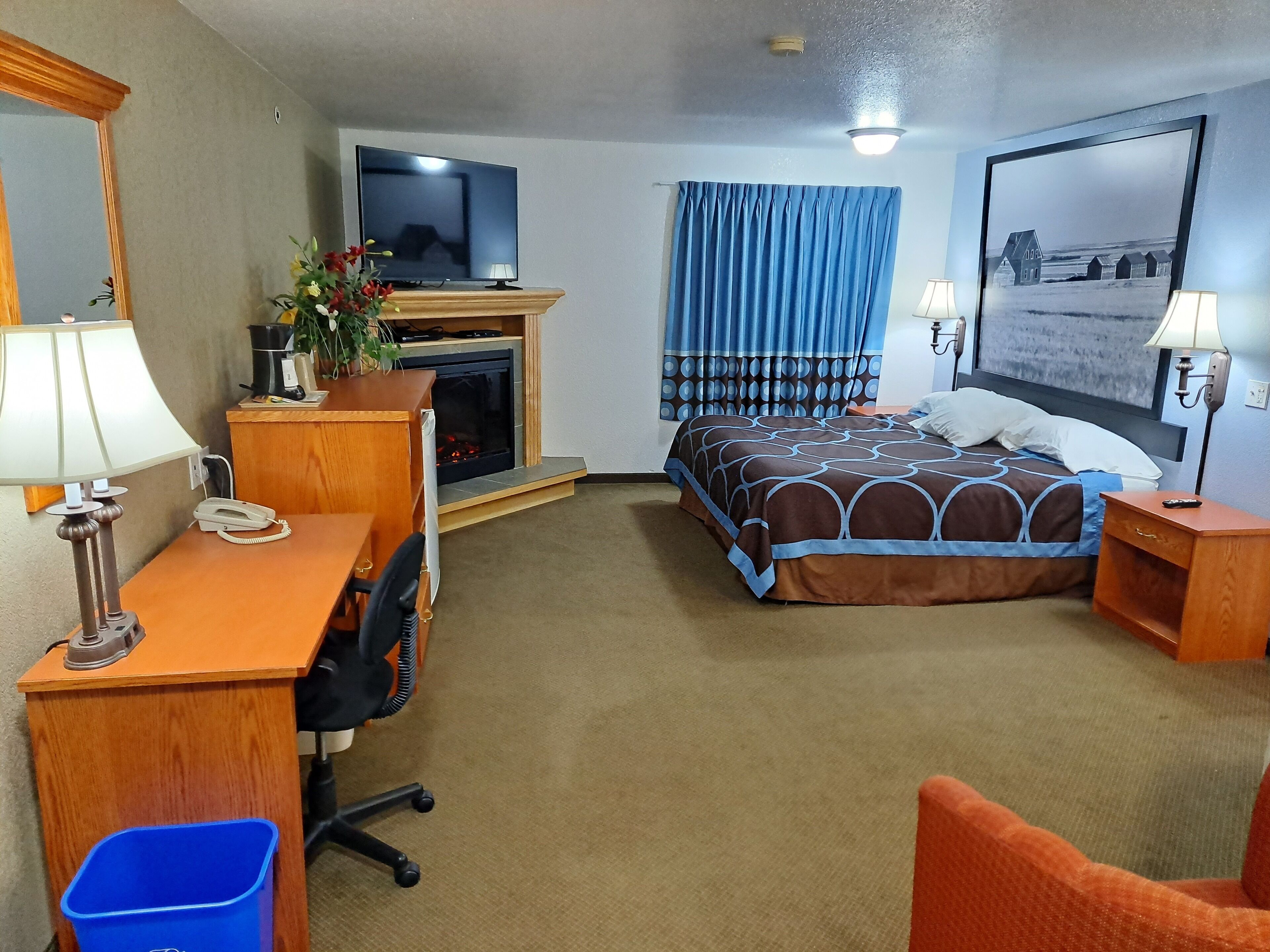 A hotel room with a bed, desk, chair, and a television.