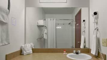 A bathroom with a sink, mirror, towel rack, shower curtain, and a hairdryer mounted on the wall.