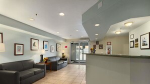A reception area with a reception desk, two sofas, framed pictures on the walls, and a tiled floor.