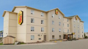 A multi-story hotel with a beige exterior, a prominent 'Super 8' sign, and a small outdoor seating area.