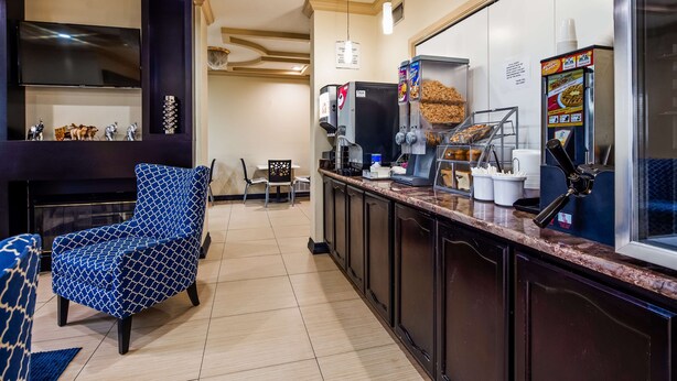 A hotel lobby with a seating area, a coffee station, and a counter with a menu. - SureStay Plus by Best Western San Antonio Airport (San Antonio)