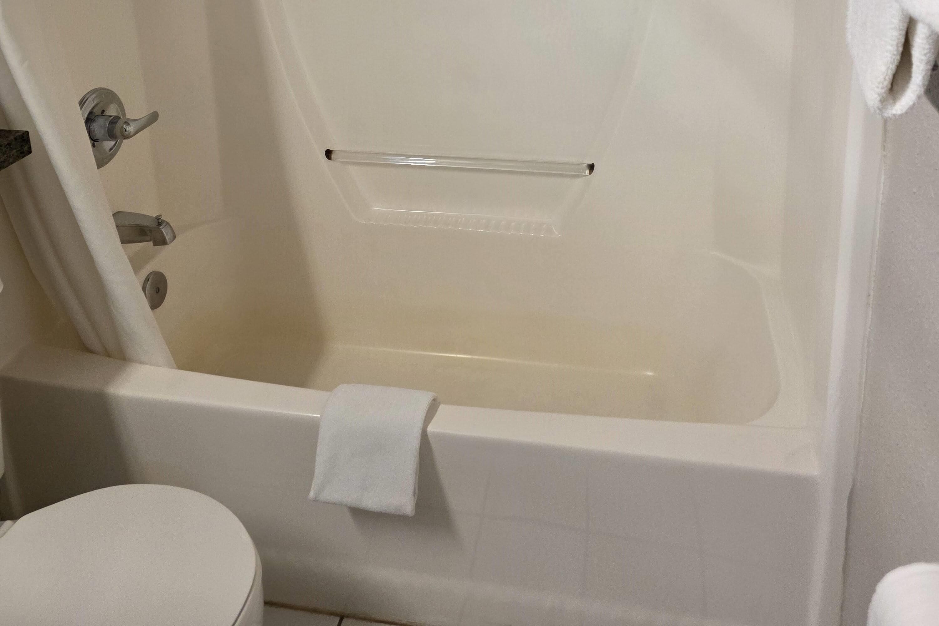 A bathroom with a bathtub, toilet, and a towel rack.