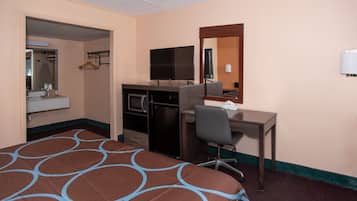 Een hotelkamer met een bed, bureau, televisie, spiegel en kitchenette.