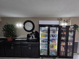 Una cocina con un reloj, un refrigerador y una planta en maceta.