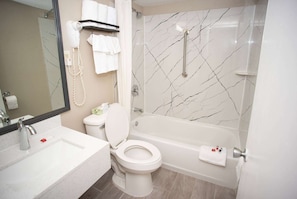 A bathroom with a toilet, sink, and bathtub. There is a towel rack with towels and a hairdryer. The walls have a marble pattern. - Super 8 by Wyndham Black Mountain/Asheville East (Black Mountain)