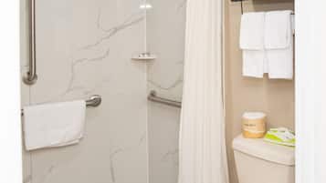 A bathroom with a shower, toilet, and a towel rack with towels.