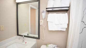 A bathroom with a sink, mirror, hair dryer, and towel rack.