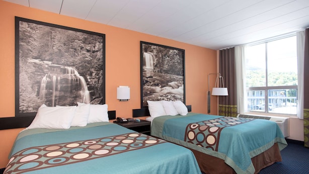 A hotel room with two beds, a large window with a view, and two framed pictures on the wall.