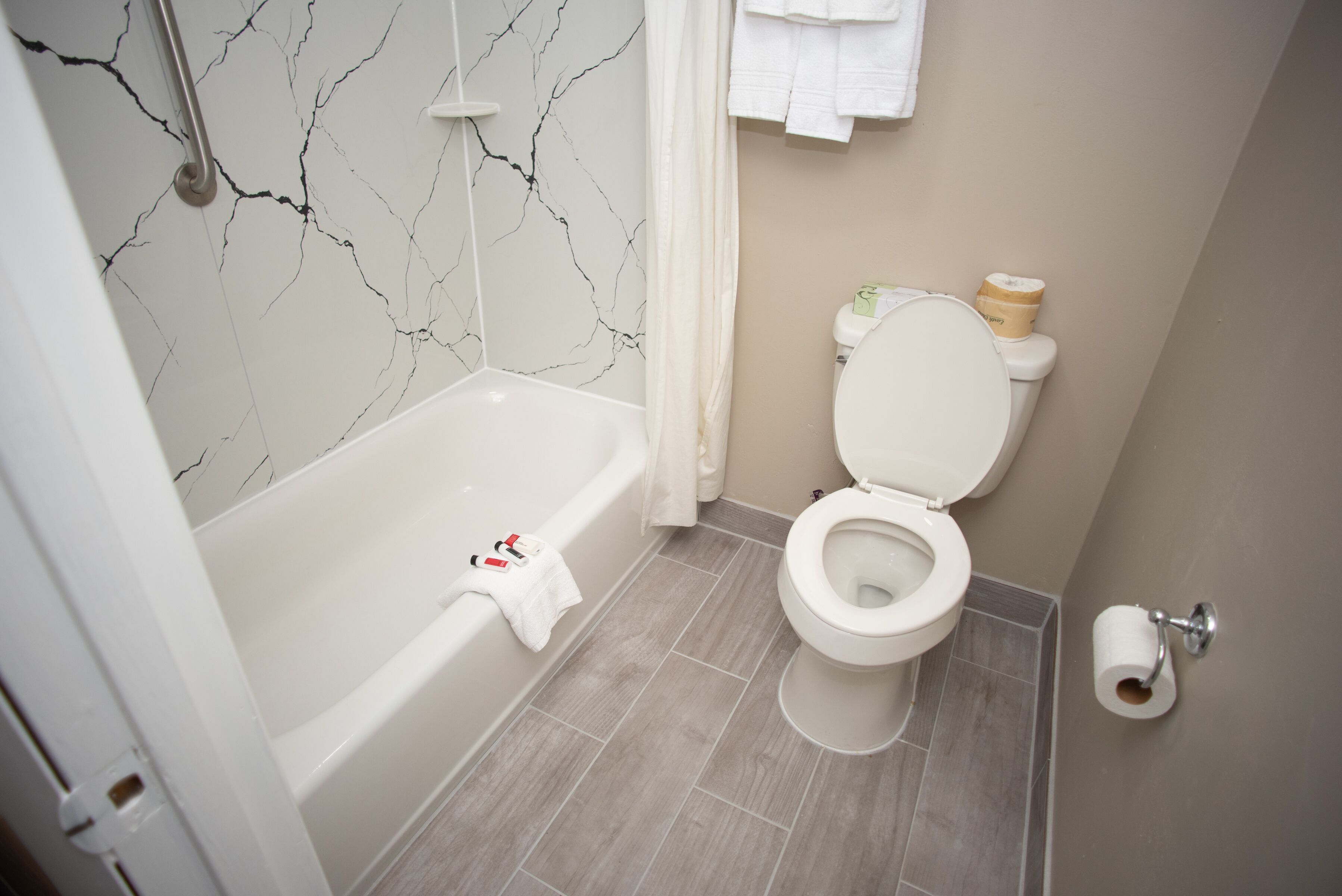 Et badeværelse med badekar, toilet og marmorvæg.