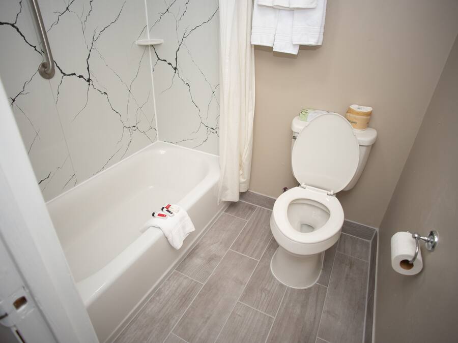 Et badeværelse med badekar, toilet og marmorvæg.