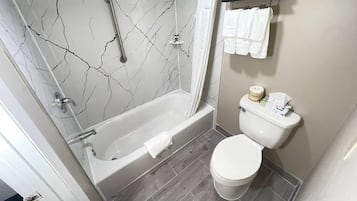 Kylpyhuone, jossa on kylpyamme, wc ja suihkuverho.