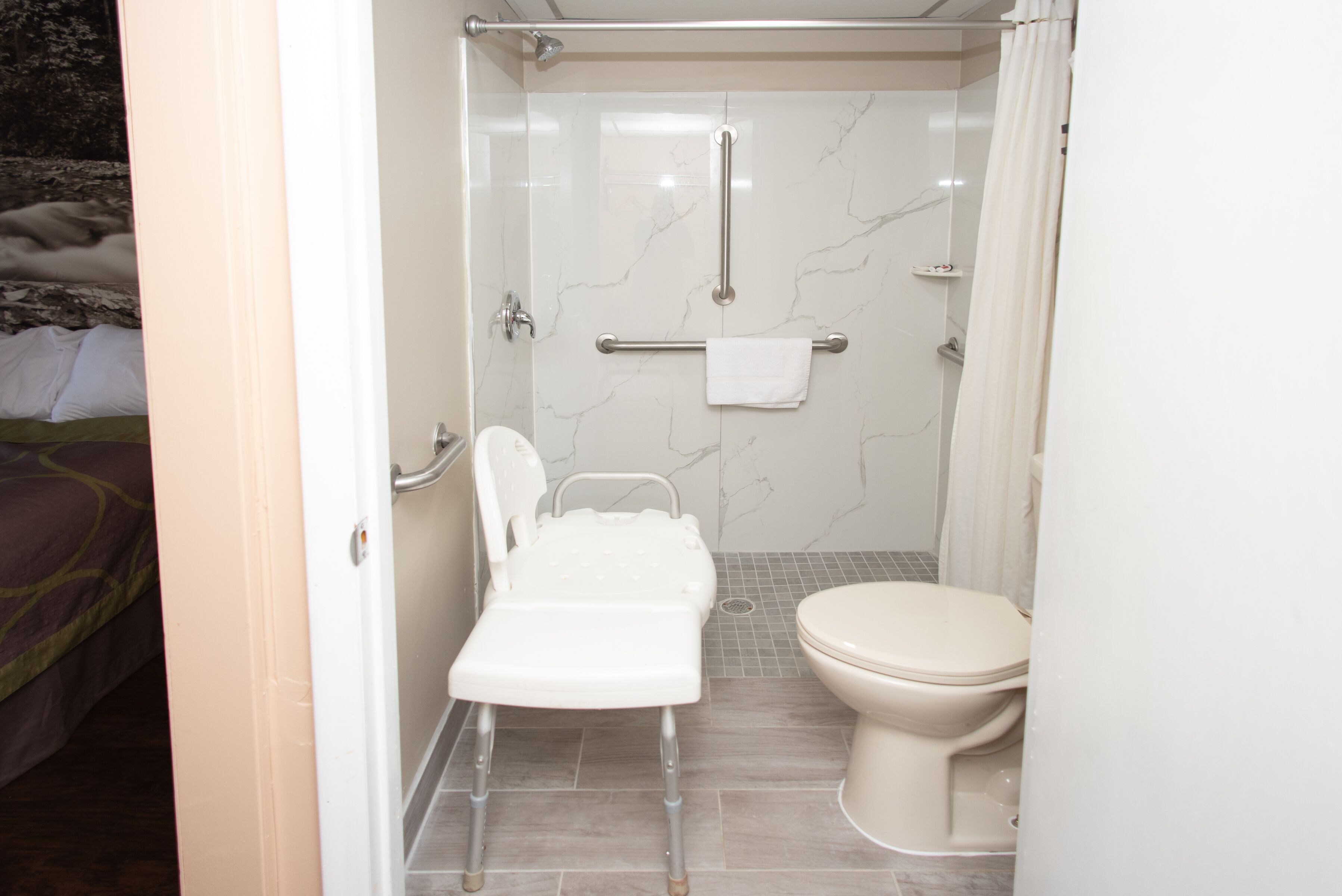 A bathroom with a shower, toilet, and a wheelchair-accessible bench.