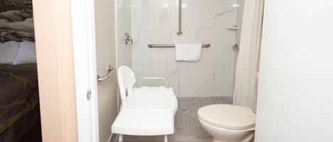 A bathroom with a shower, toilet, and a wheelchair-accessible bench.