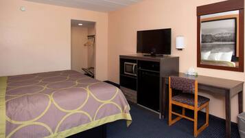 Une chambre d’hôtel équipée d’un lit, d’un bureau avec une télévision, d’une chaise et d’un four à micro-ondes.