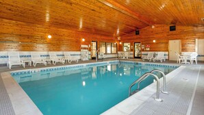 An indoor swimming pool with wooden walls and tiled floor, surrounded by white lounge chairs. - Comfort Inn Fremont (Fremont)