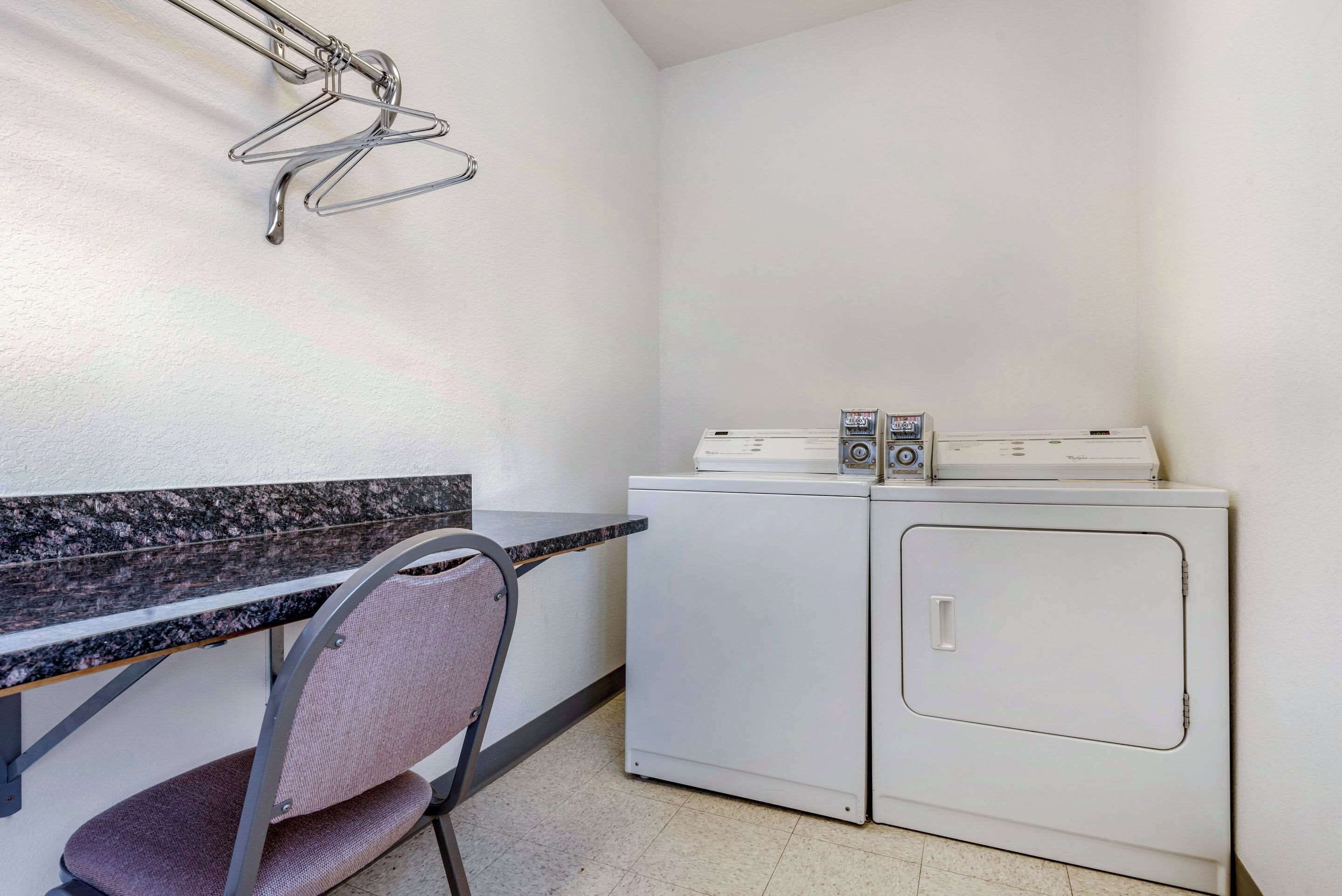 Un espace buanderie comprenant un lave-linge, un sèche-linge, une chaise et un plan de travail.