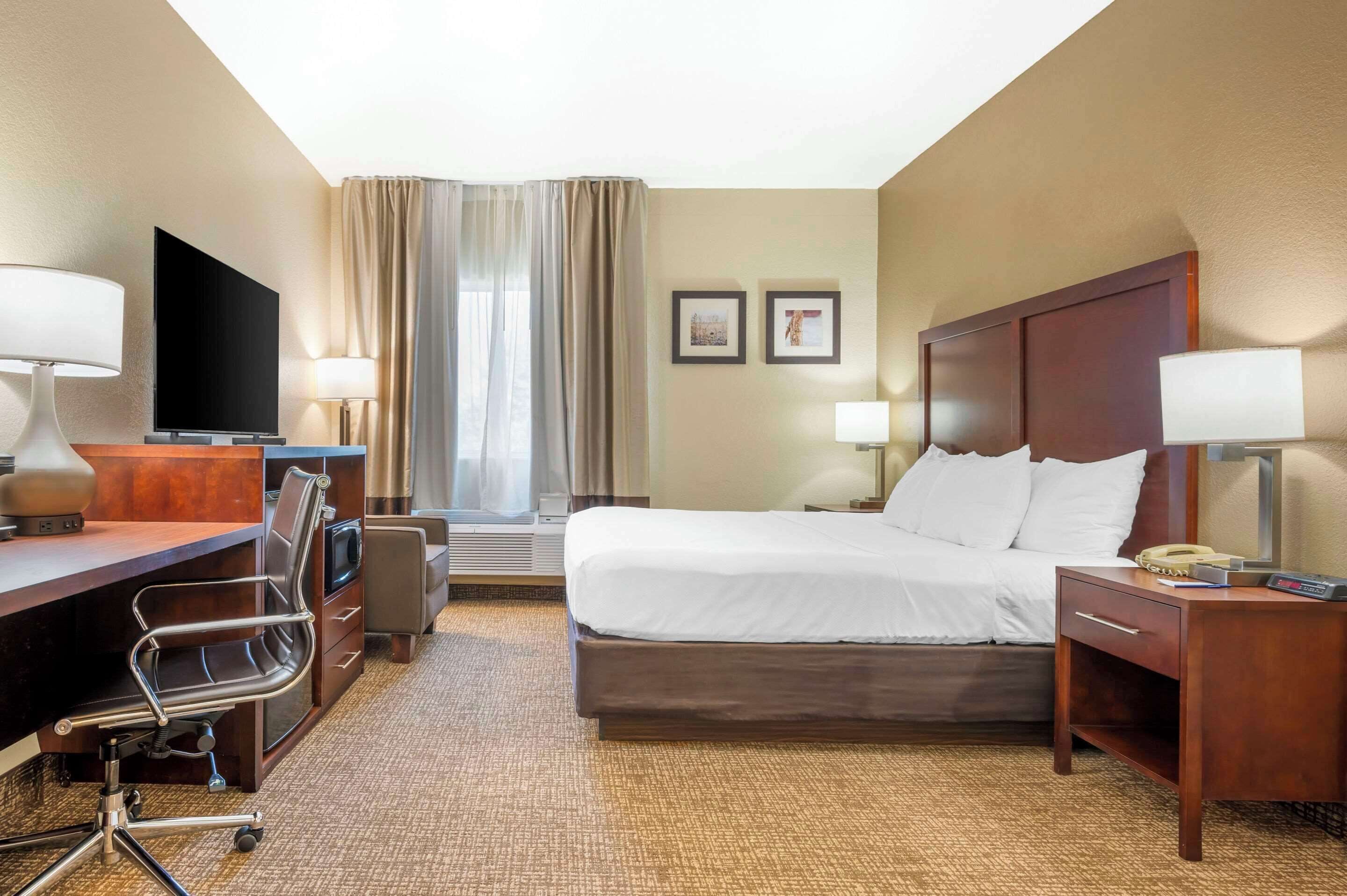 Une chambre d’hôtel équipée d’un lit, d’un bureau, d’une chaise, d’une télévision et de deux lampes.