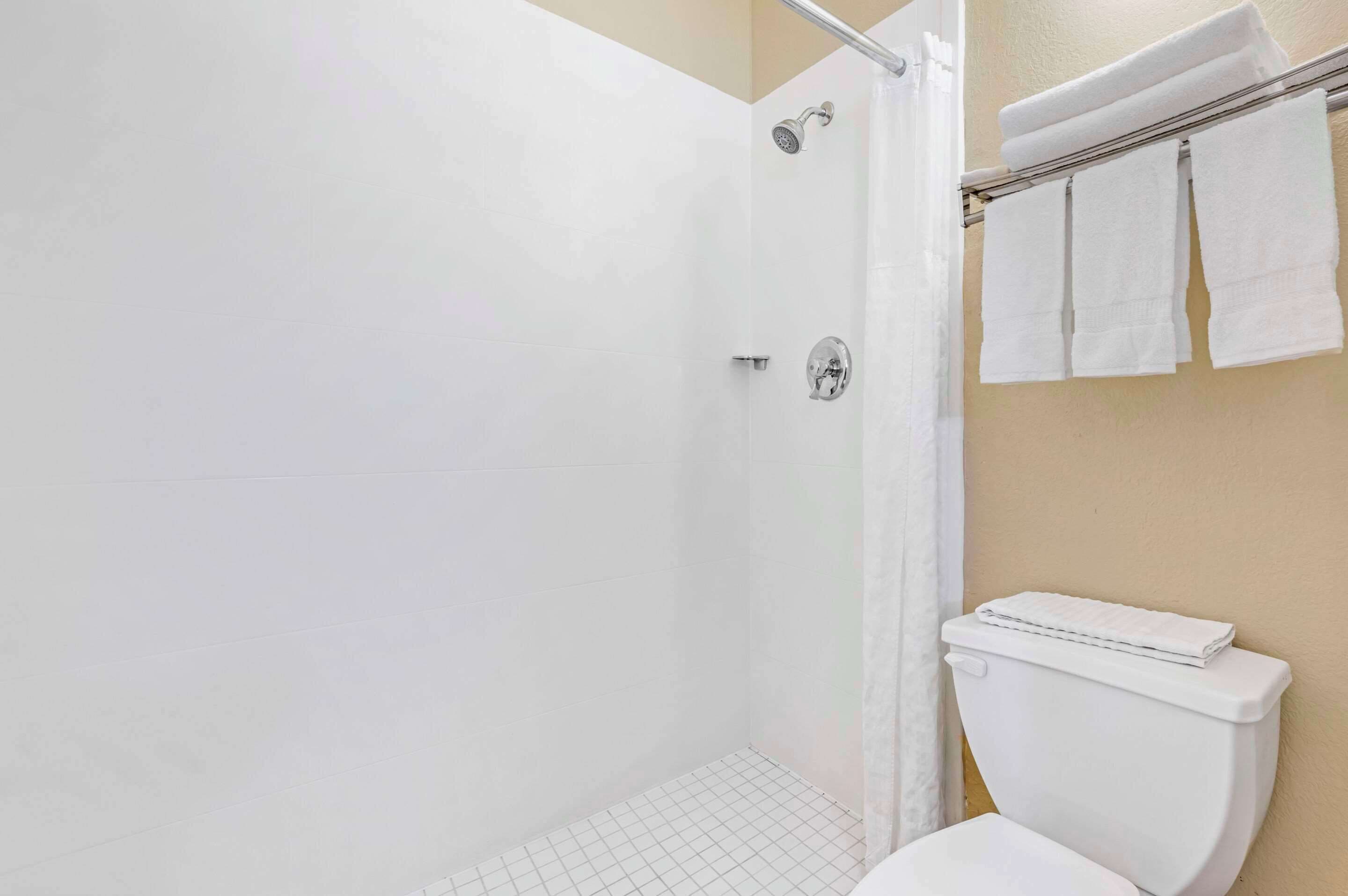 Un baño con ducha, inodoro y toallero.