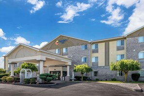 A Comfort Inn hotel with a two-story building, a covered entrance, and a landscaped front yard with trees and shrubs.