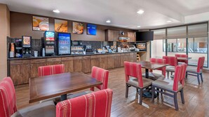 A modern restaurant with wooden cabinets, red upholstered chairs, and a counter with a coffee machine and a refrigerator. - Comfort Inn Fremont (Fremont)