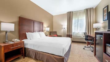 A hotel room with a large bed, bedside tables, a desk, a chair, and a TV.