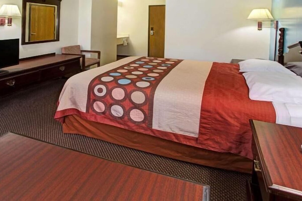 A hotel room with a bed, a desk, a television, and a lamp.