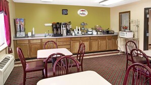 Ein Frühstücksbereich mit Theke, Kaffeeautomaten und Sitzgelegenheiten.