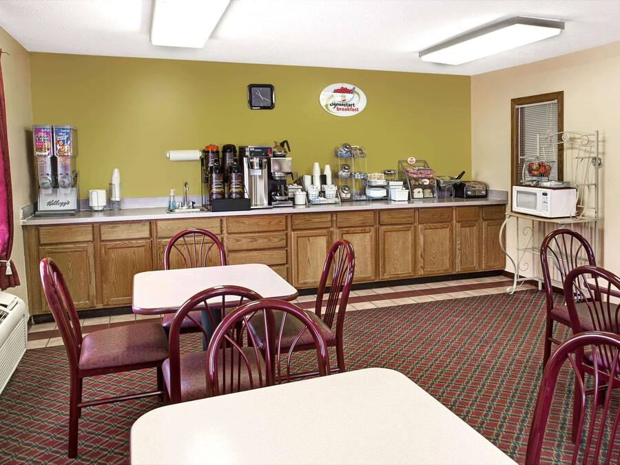 A breakfast area with a counter, coffee machines, and seating.
