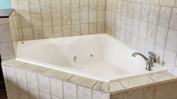 A rectangular bathtub with a single faucet, set against a tiled wall with floral patterns.