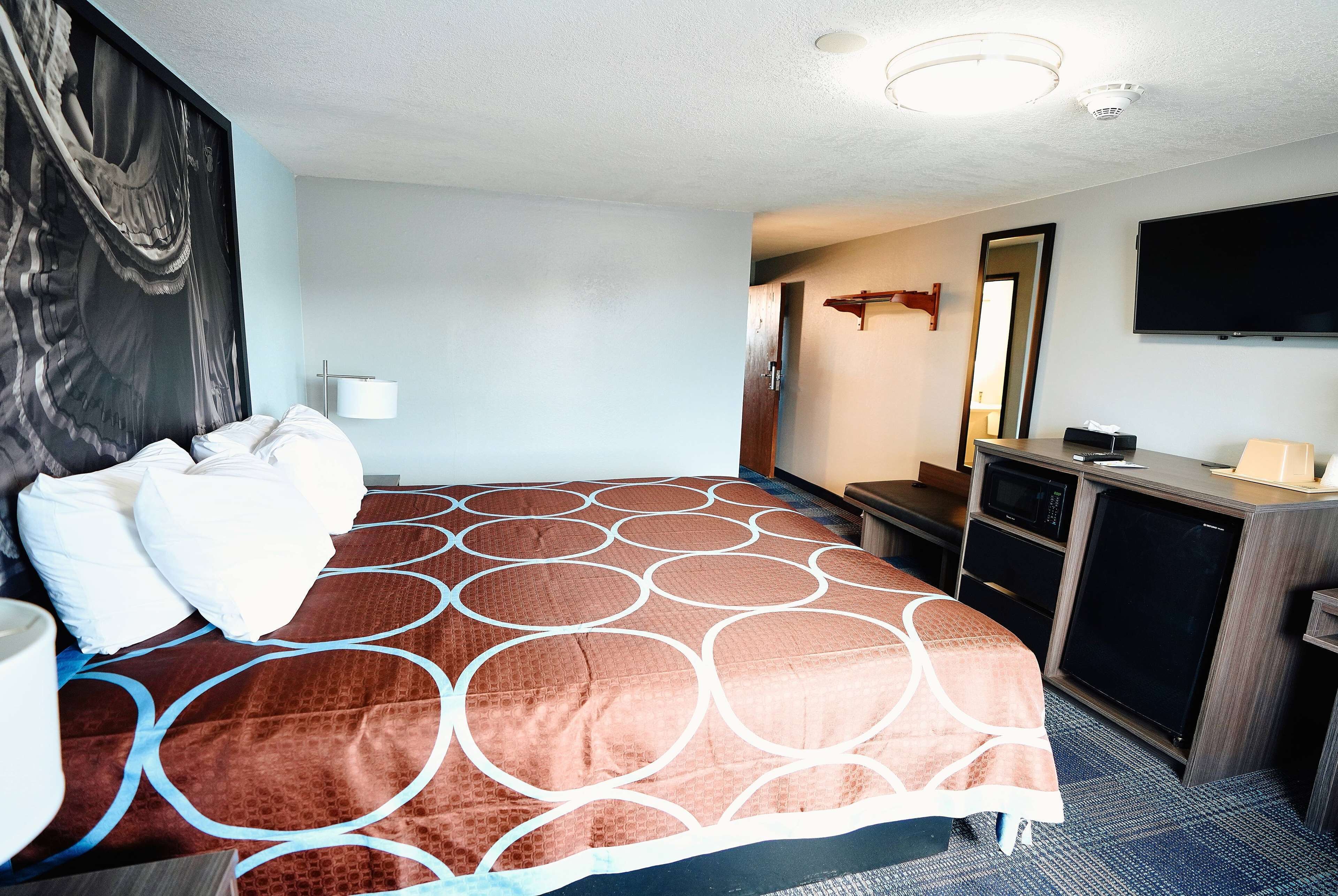 A hotel room with a large bed, a desk with a computer, a television, and a mirror.