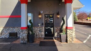 A hotel entrance with a stone facade, a black door marked with the letter 'A', and two wall-mounted light fixtures.