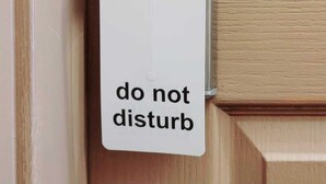 A door with a 'do not disturb' sign attached to a metallic handle.