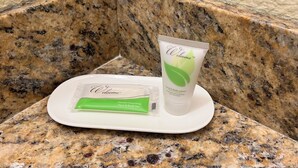 A Welcome™ hand and body lotion and a green bar of gentle cleansing face and body bar on a white plate on a granite countertop.