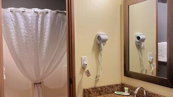 A bathroom with a shower curtain, a hairdryer, a sink, and a mirror.