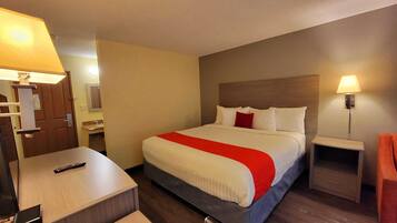Una habitación de hotel con cama, mesitas de noche, escritorio y una silla.