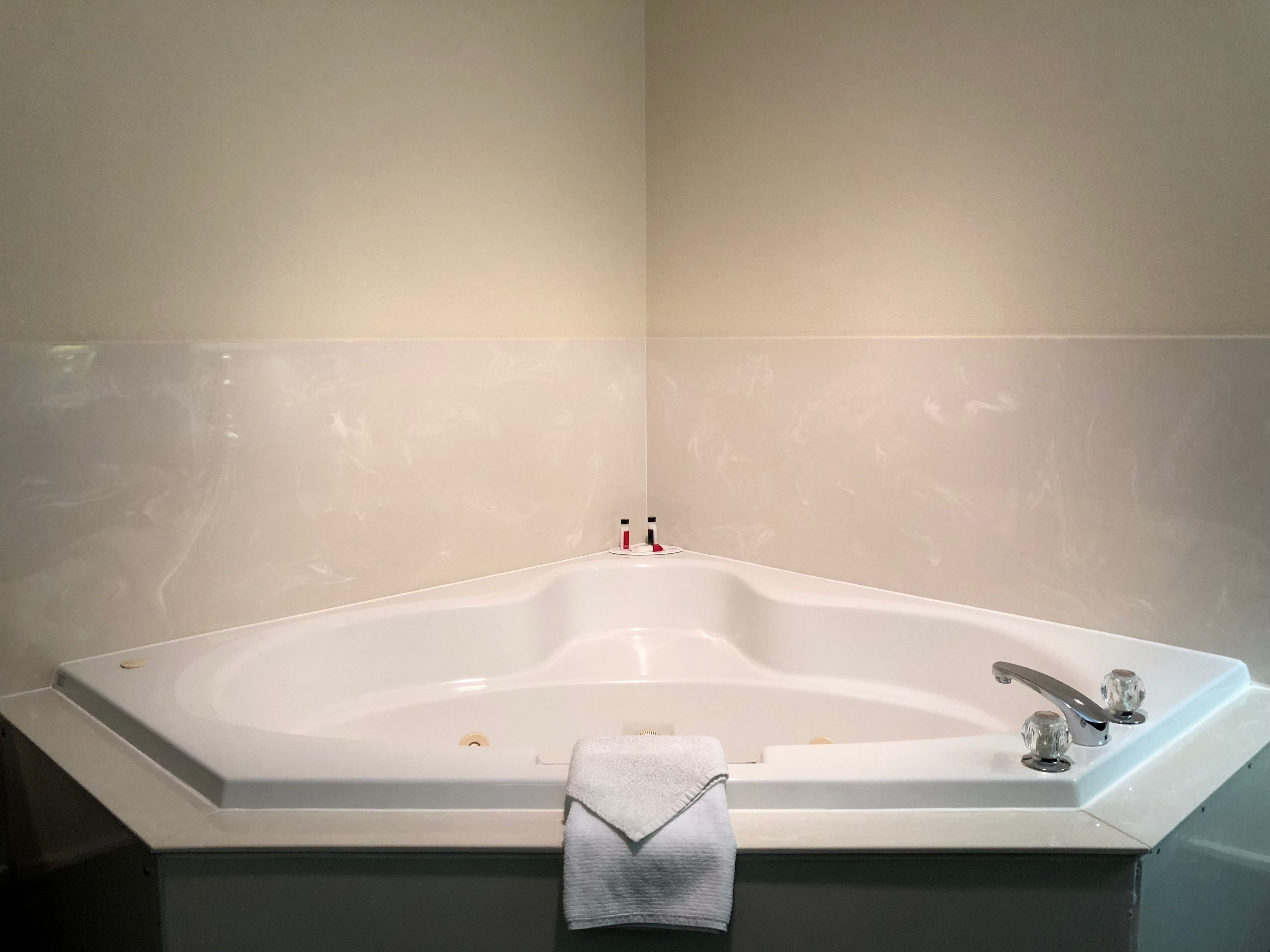 A large, freestanding bathtub in a bathroom with a towel draped over the edge.
