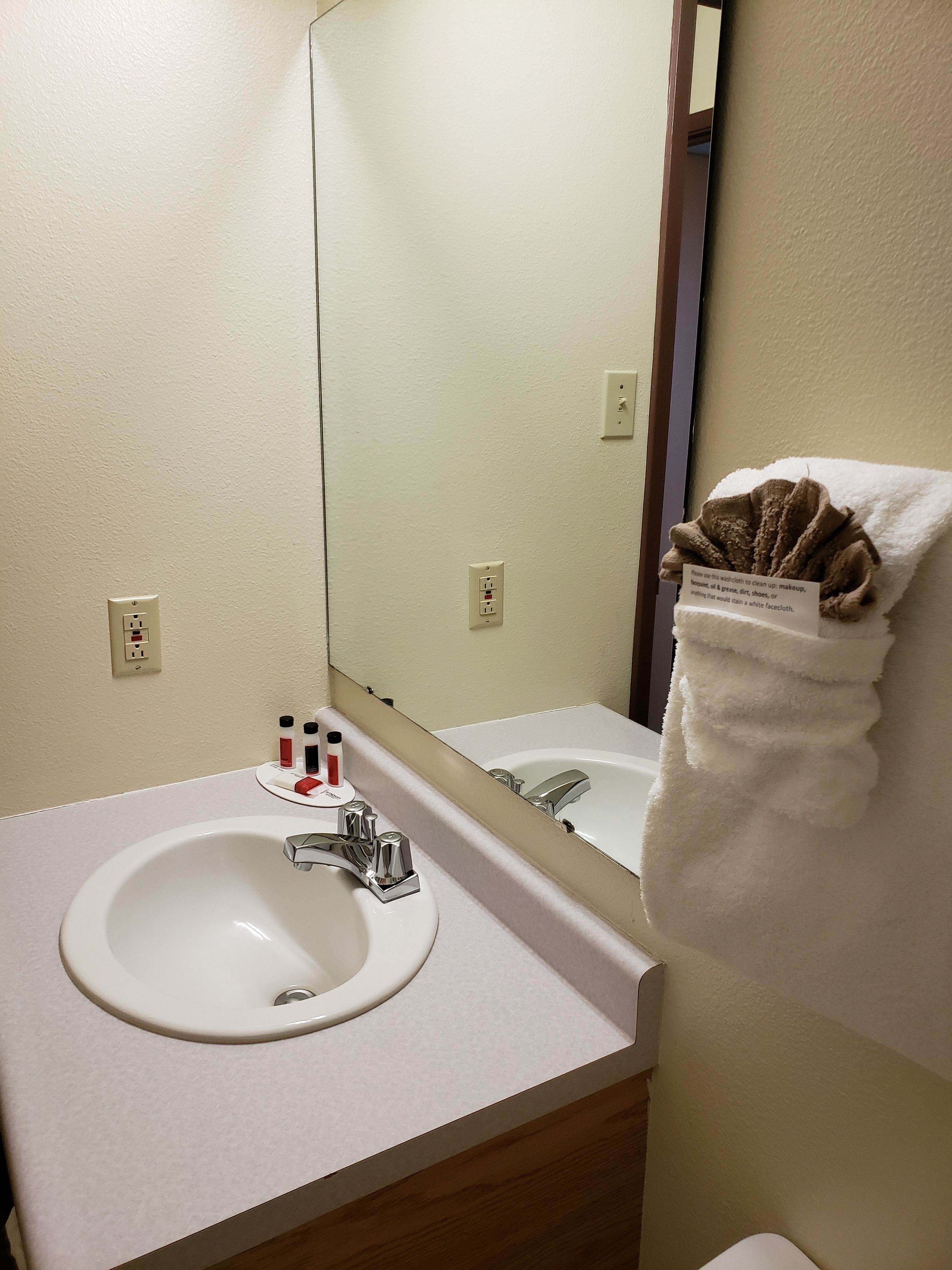 A hotel bathroom with a white sink, a mirror, and a towel rack with a towel.