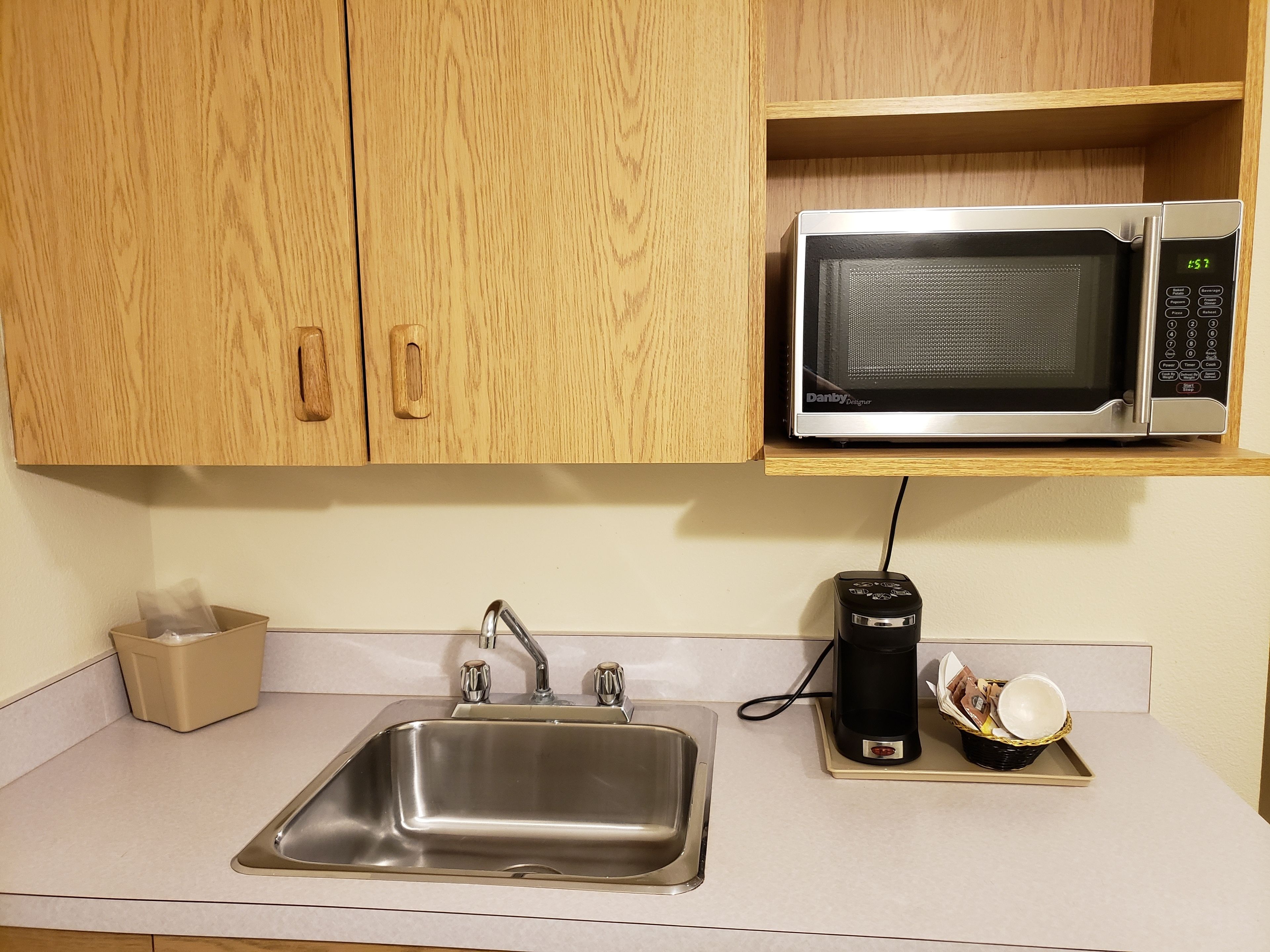 A kitchen with a stainless steel sink, a microwave, and a coffee maker on a tray.