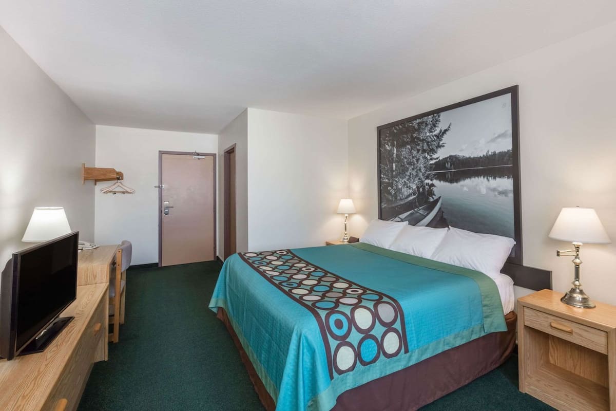 Una habitación de hotel con cama, televisión, escritorio y puerta.
