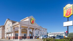 A Super 8 hotel with a prominent sign, multiple parking spaces, and a clear blue sky. - Super 8 by Wyndham Moose Jaw SK (Moose Jaw)