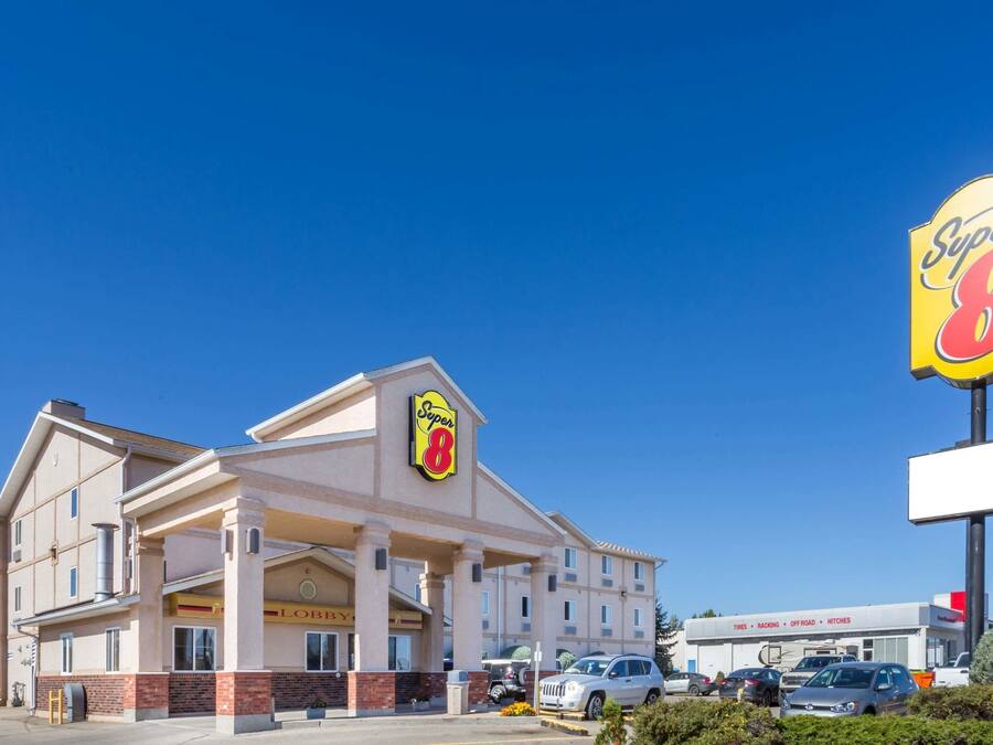 Un hotel Super 8 con un letrero llamativo, varios espacios de estacionamiento y un cielo azul despejado.