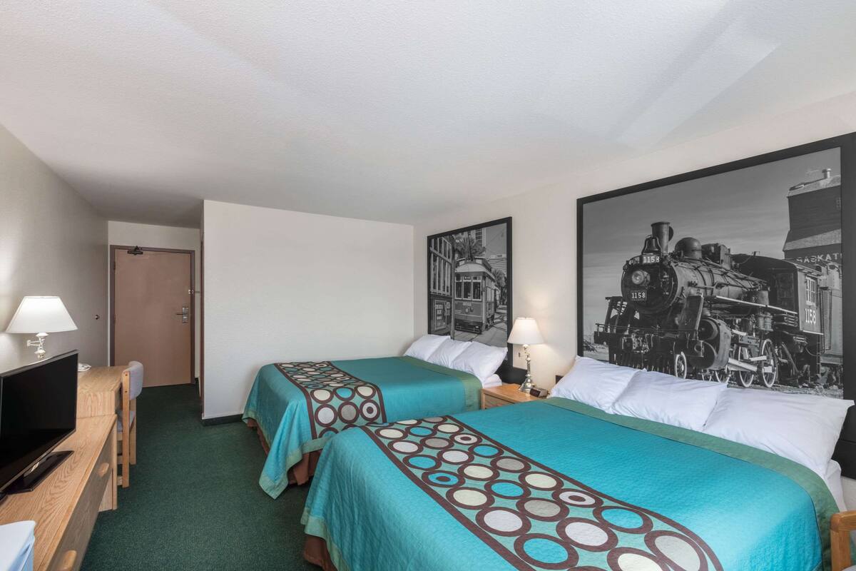 Habitación de hotel con dos camas, televisión, escritorio y puerta.