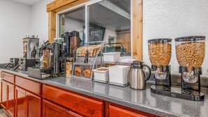 Una barra de desayuno con máquinas de café, dispensadores de cereales y diferentes recipientes con alimentos.