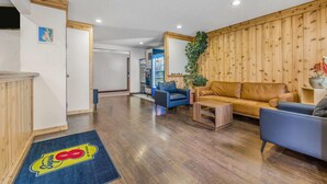 Amplia sala de estar con pared de madera, un sofá, una mesa de centro y un sillón azul.