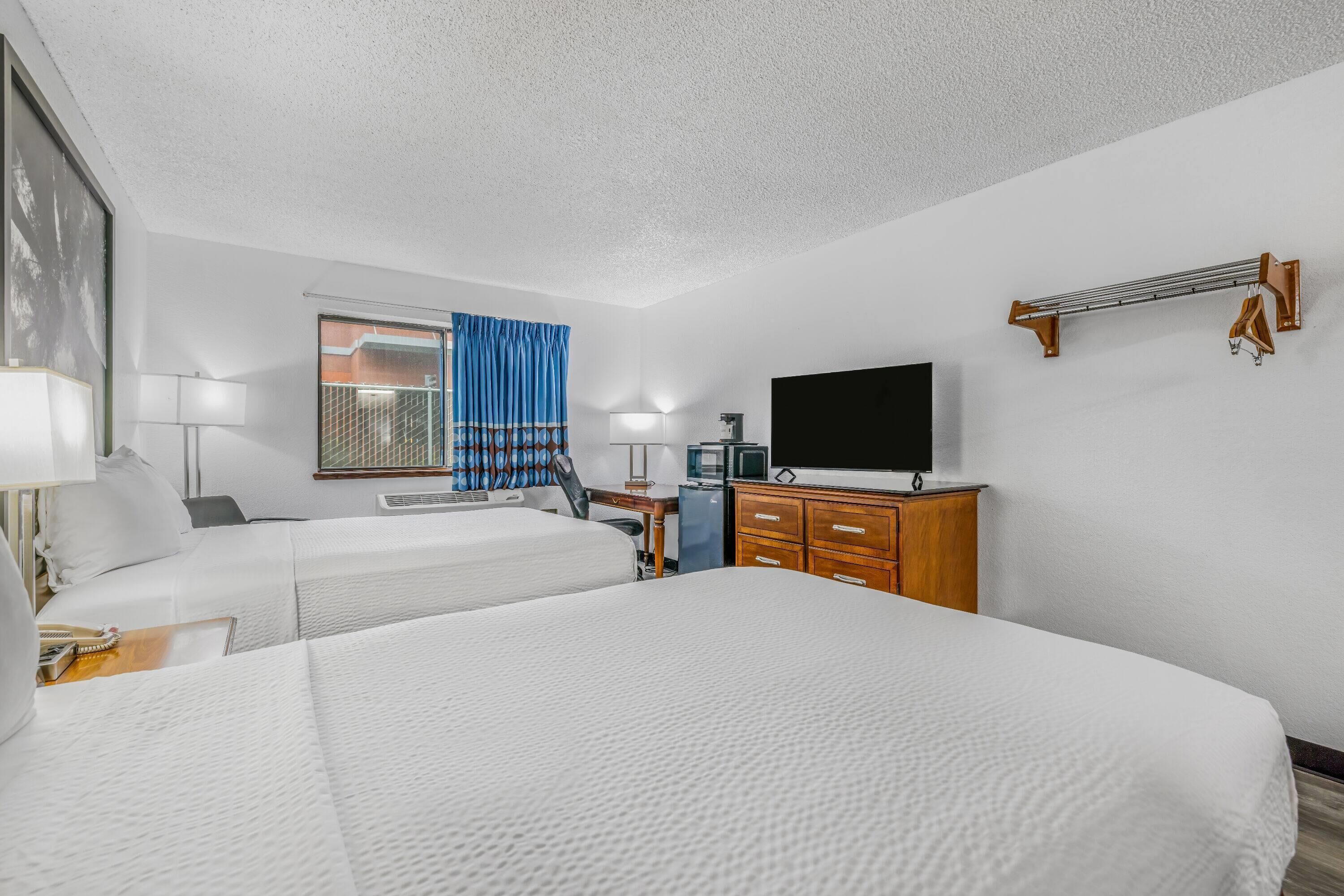 A hotel room with two beds, a desk, a television, and a wardrobe.