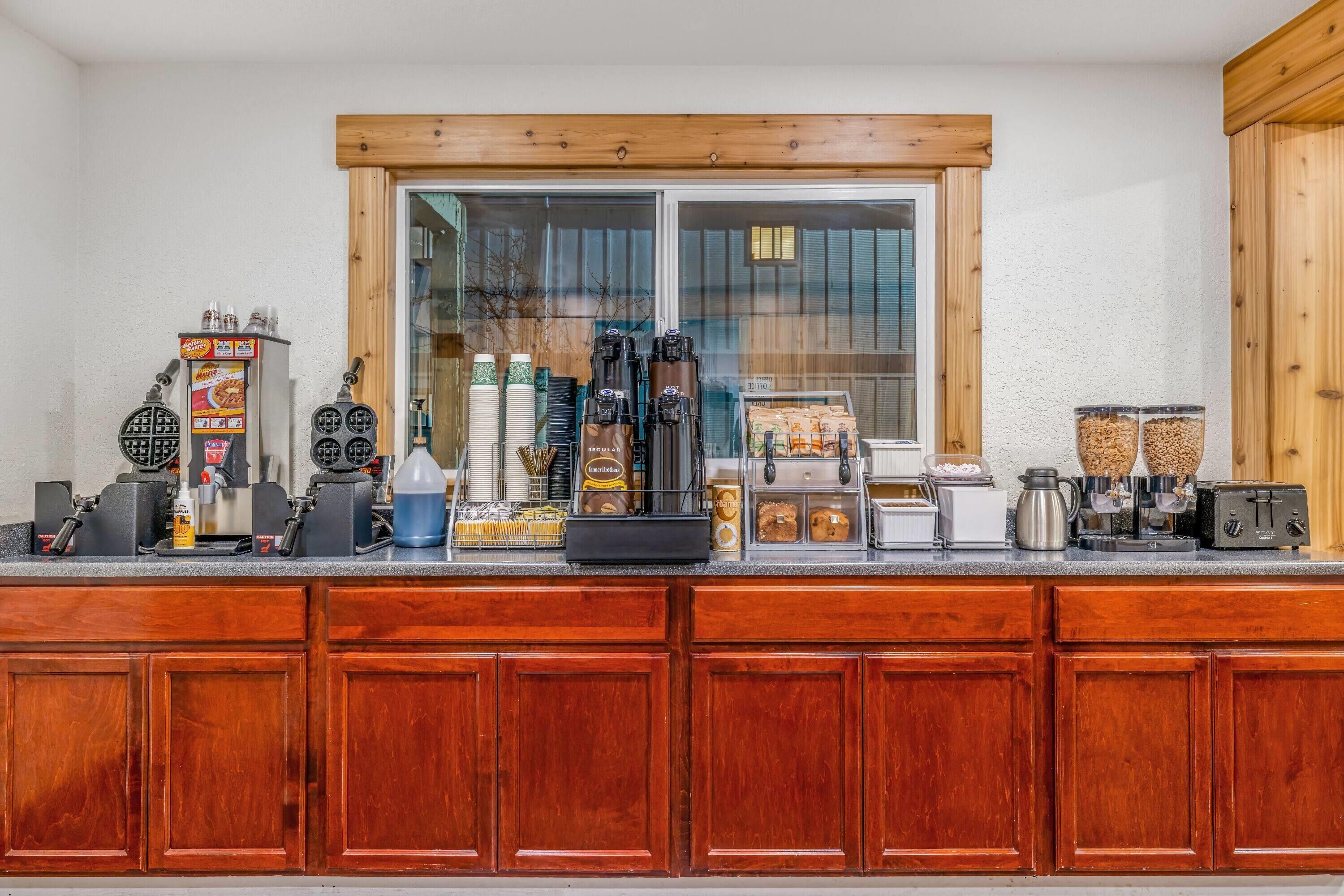 Eine Küchenarbeitsplatte mit Waffeleisen, Kaffeeautomaten und verschiedenen Lebensmitteln.