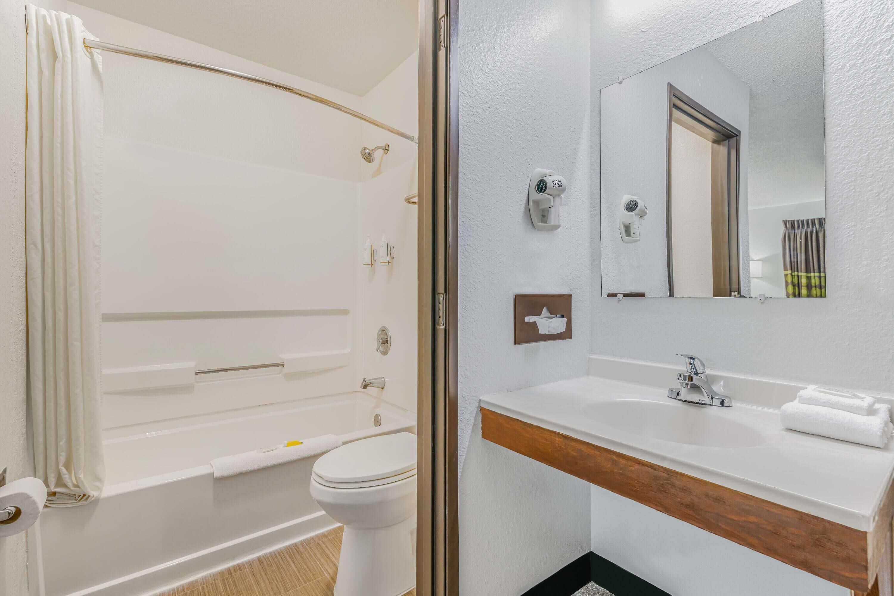 Un baño con bañera, inodoro y lavabo con espejo.