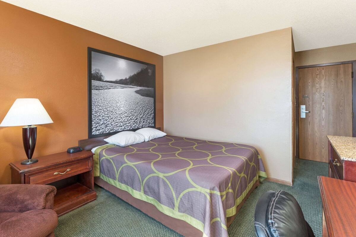 Une chambre d’hôtel comprenant un lit, une table de chevet, une lampe, une chaise et un bureau.