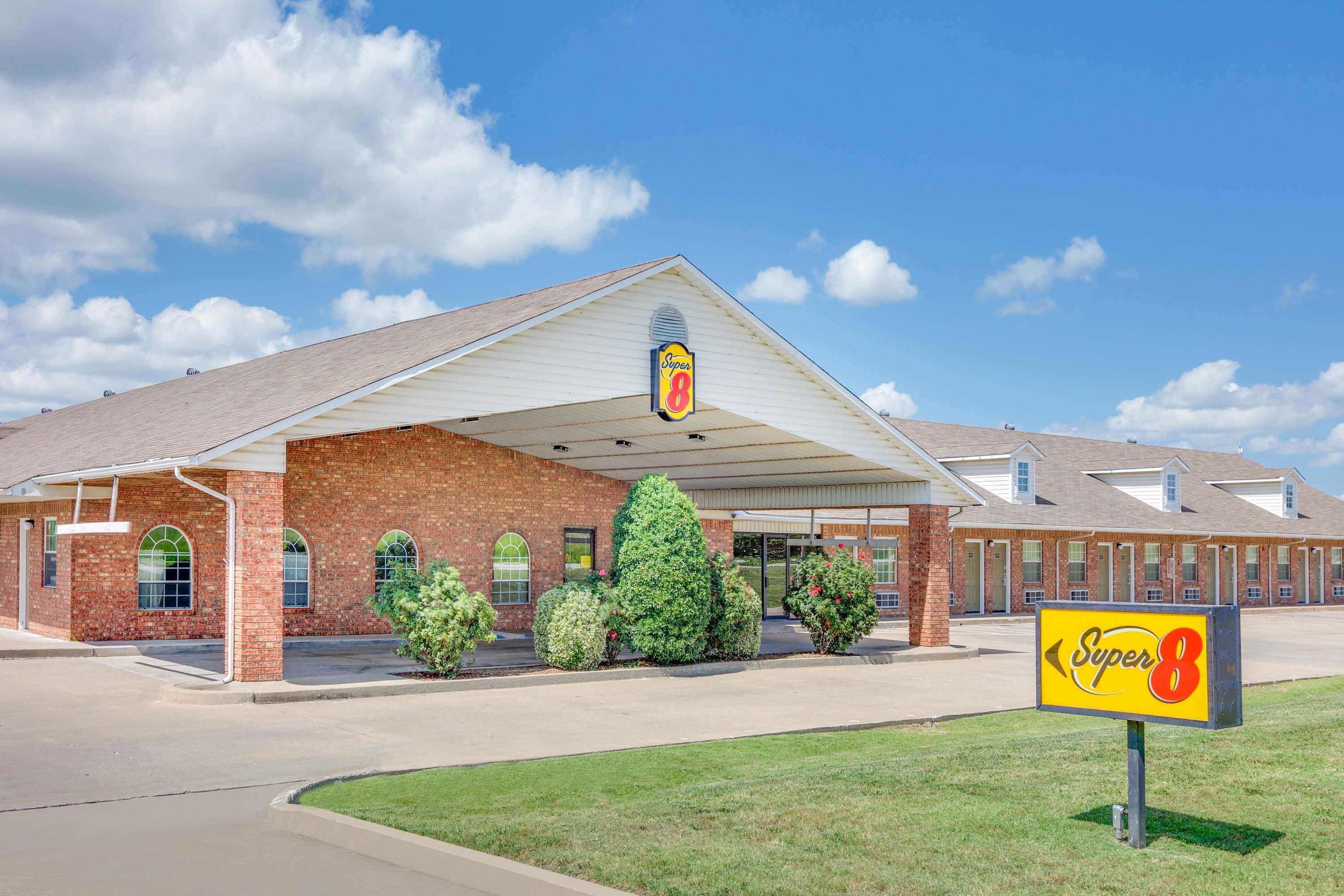 A Super 8 motel with a brick facade, large windows, and a covered parking area.